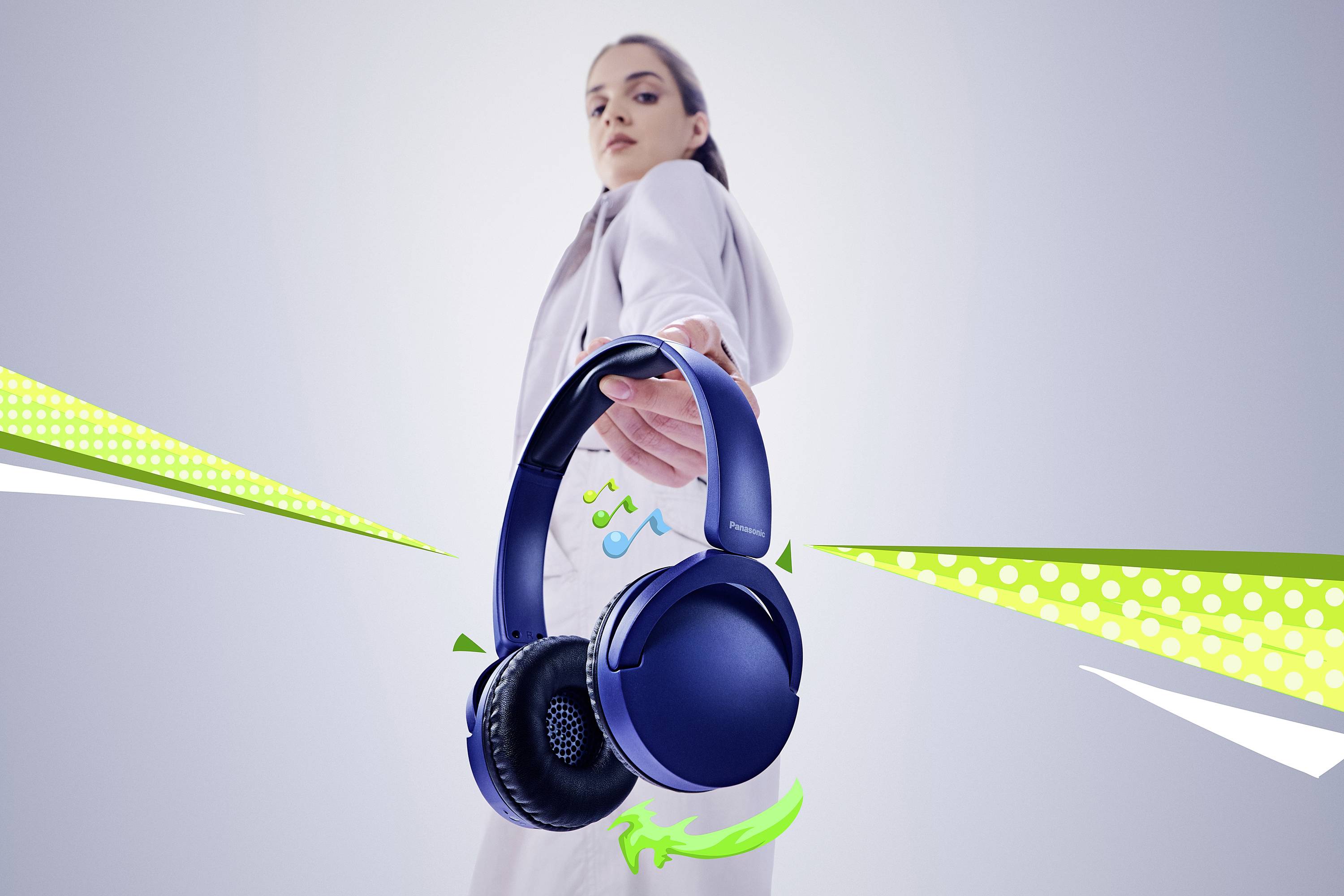 Osoba ubrana w jasny strój trzymająca niebieskie słuchawki, z zielonymi i żółtymi elementami graficznymi sugerującymi muzykę i ruch.