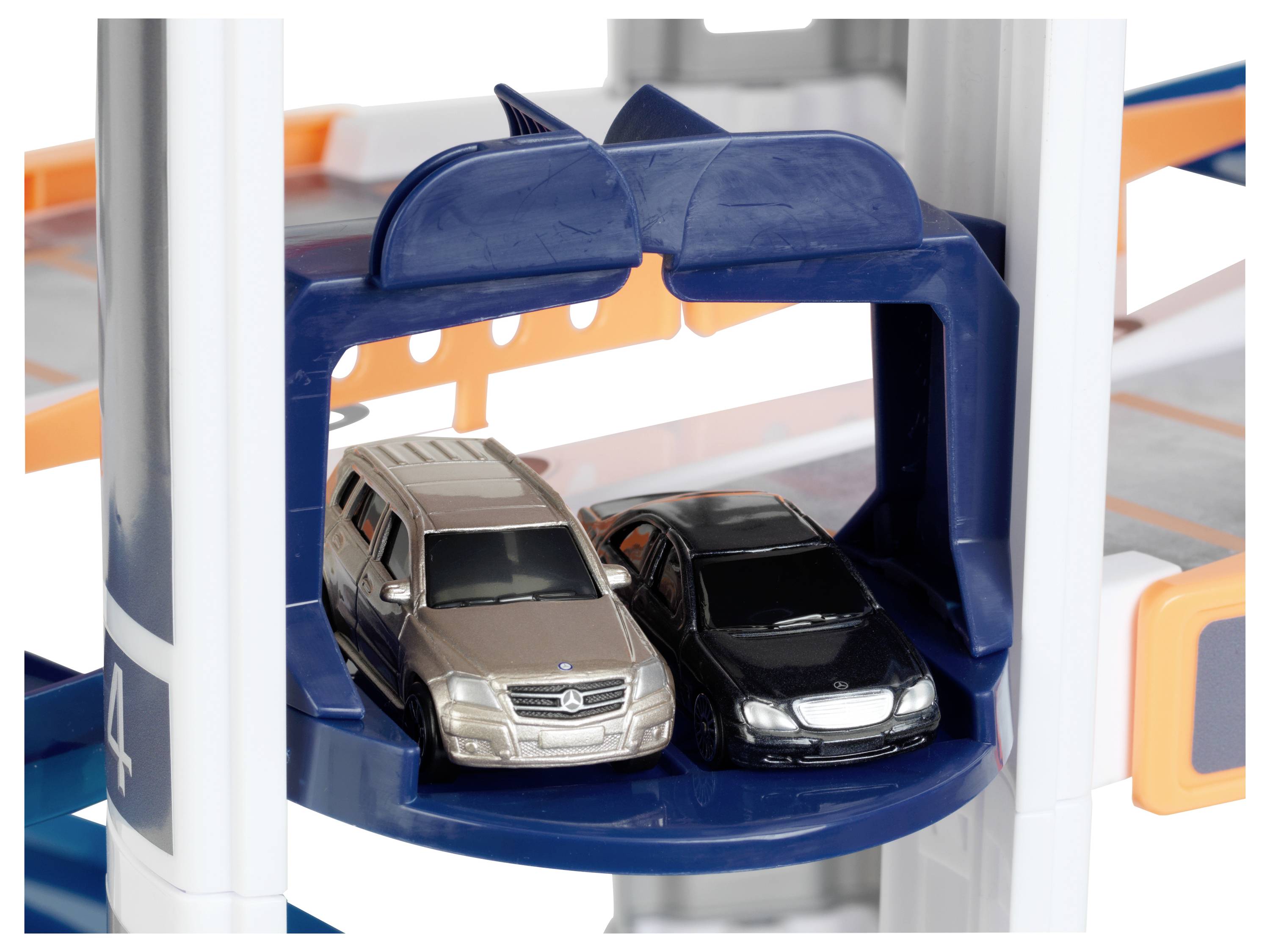 Dwie zabawkowe samochodziki, jeden w kolorze beżowym, a drugi czarnym, zaparkowane blisko siebie na niebieskiej, okrągłej platformie przypominającej parking.