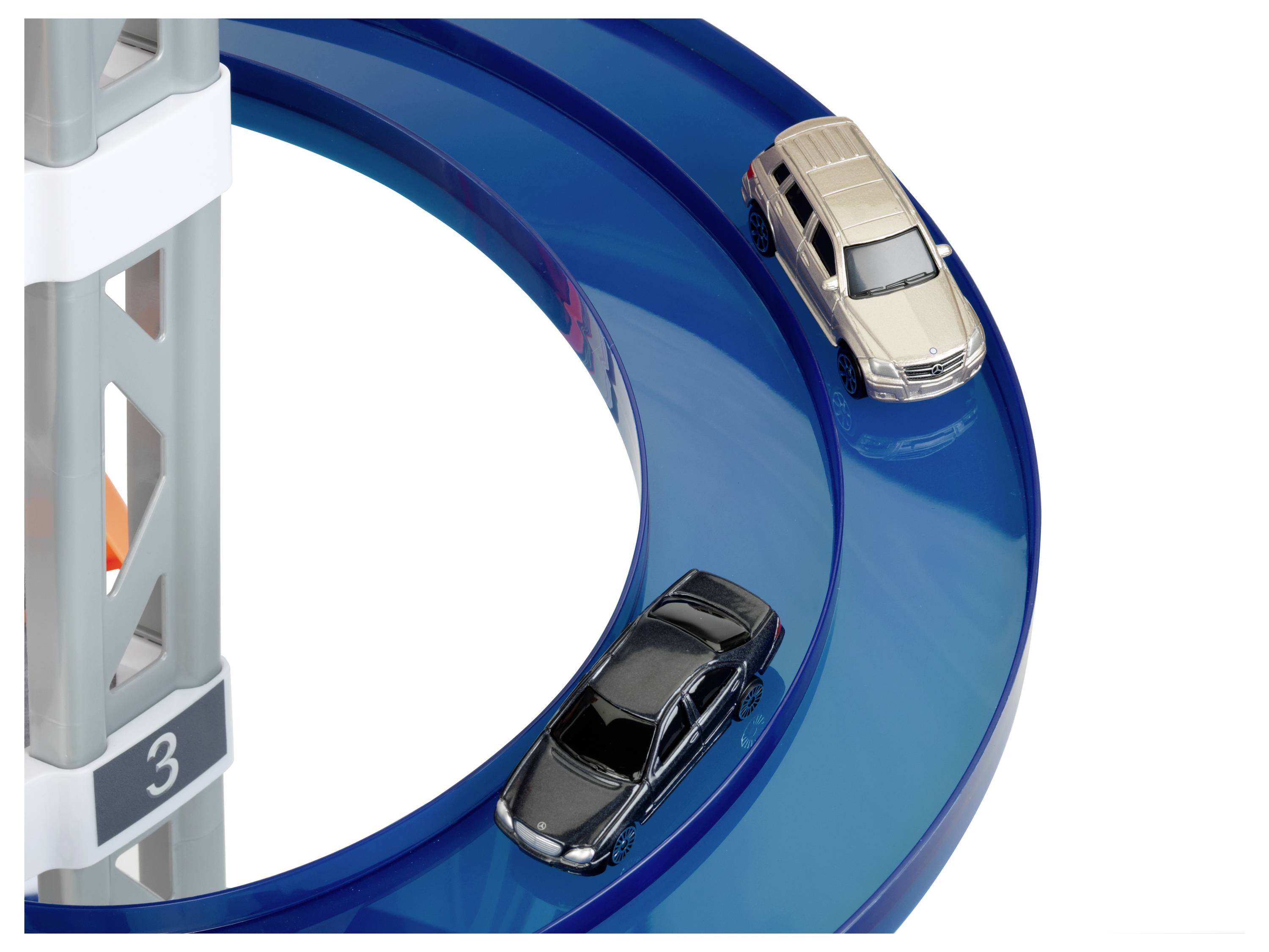 'Dwie zabawkowe samochodziki, jeden czarny, a drugi beżowy, jeżdżą po niebieskim spiralnym torze, częściowo osłoniętym szarą konstrukcją nośną oznaczoną numerem 3.'