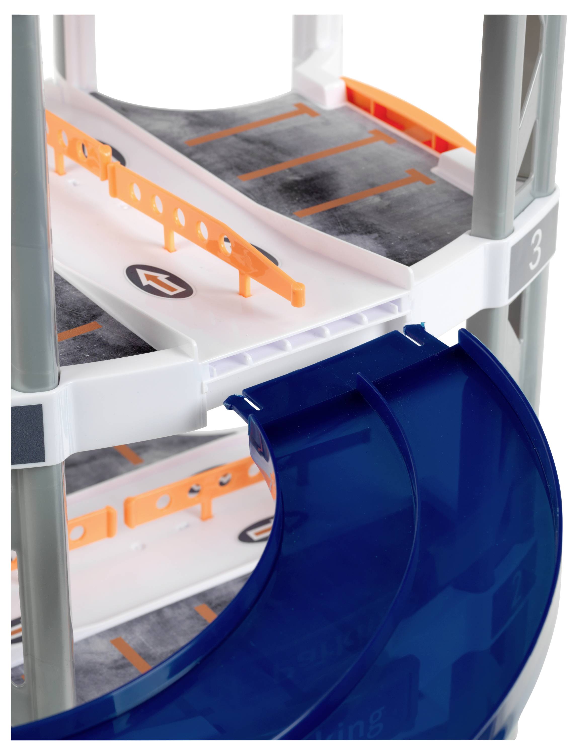 Zabawkowy parking wielopoziomowy z pomarańczowymi barierkami i niebieską spiralną zjazdową dla małych samochodów.