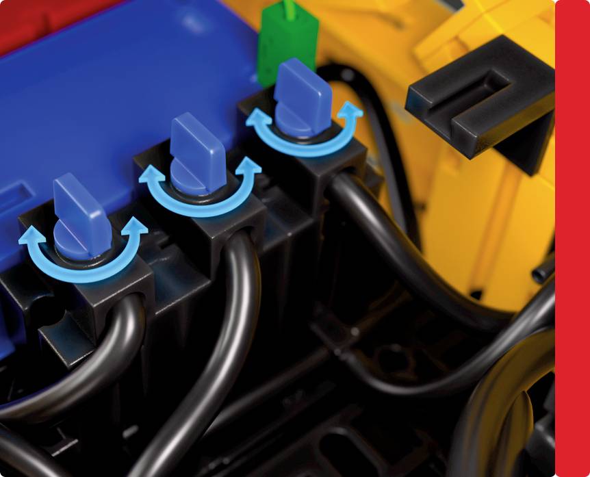 Trzy czarne przełączniki z niebieskimi strzałkami wskazującymi obrót zgodny z ruchem wskazówek zegara, połączone czarnymi kablami. W pobliżu jasne niebieskie, zielone i żółte elementy.