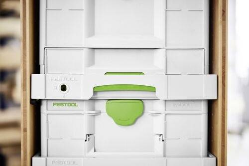 Białe pudełka magazynowe z zielonymi zatrzaskami, ułożone na drewnianym regale, oznaczone etykietą 'FESTOOL'.