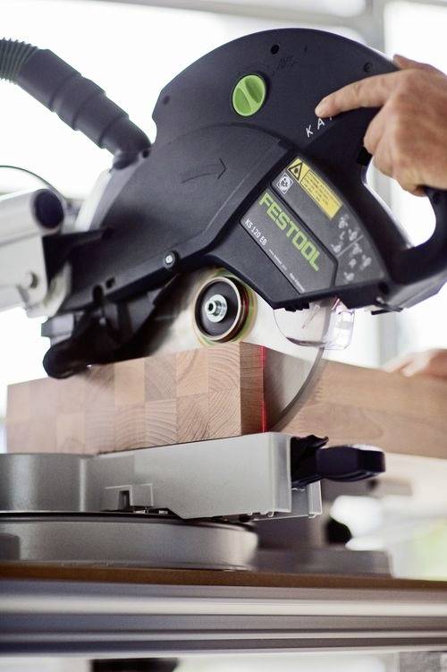 Osoba używa piły tarczowej do cięcia grubego drewnianego bloku, prezentując precyzyjne narzędzia i technikę stolarską.