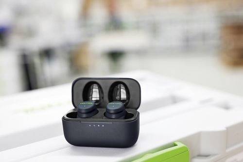 Bezprzewodowe słuchawki douszne w otwartym etui ładującym na stole, z rozmytym tłem.