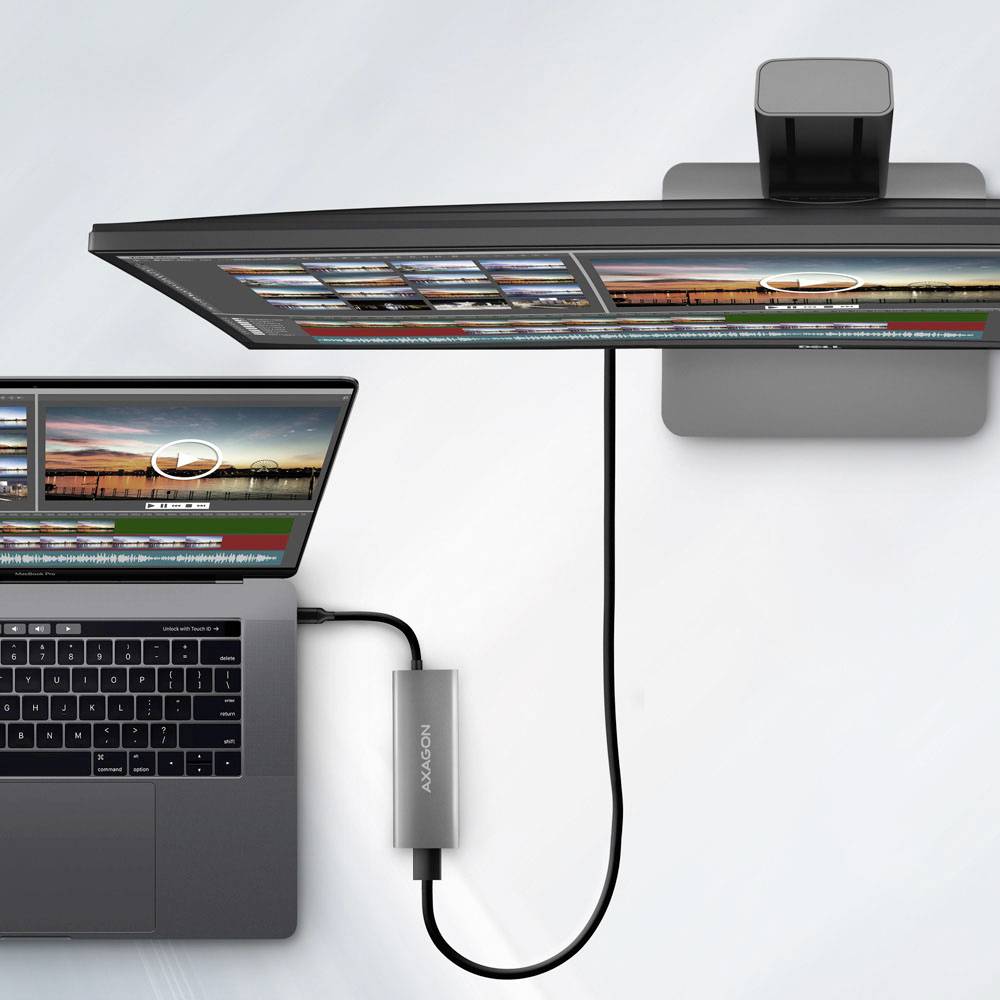 Laptop podłączony do zakrzywionego monitora, wyświetlający identyczne ekrany oprogramowania do edycji wideo, podkreślający produktywną konfigurację z podwójnym ekranem.