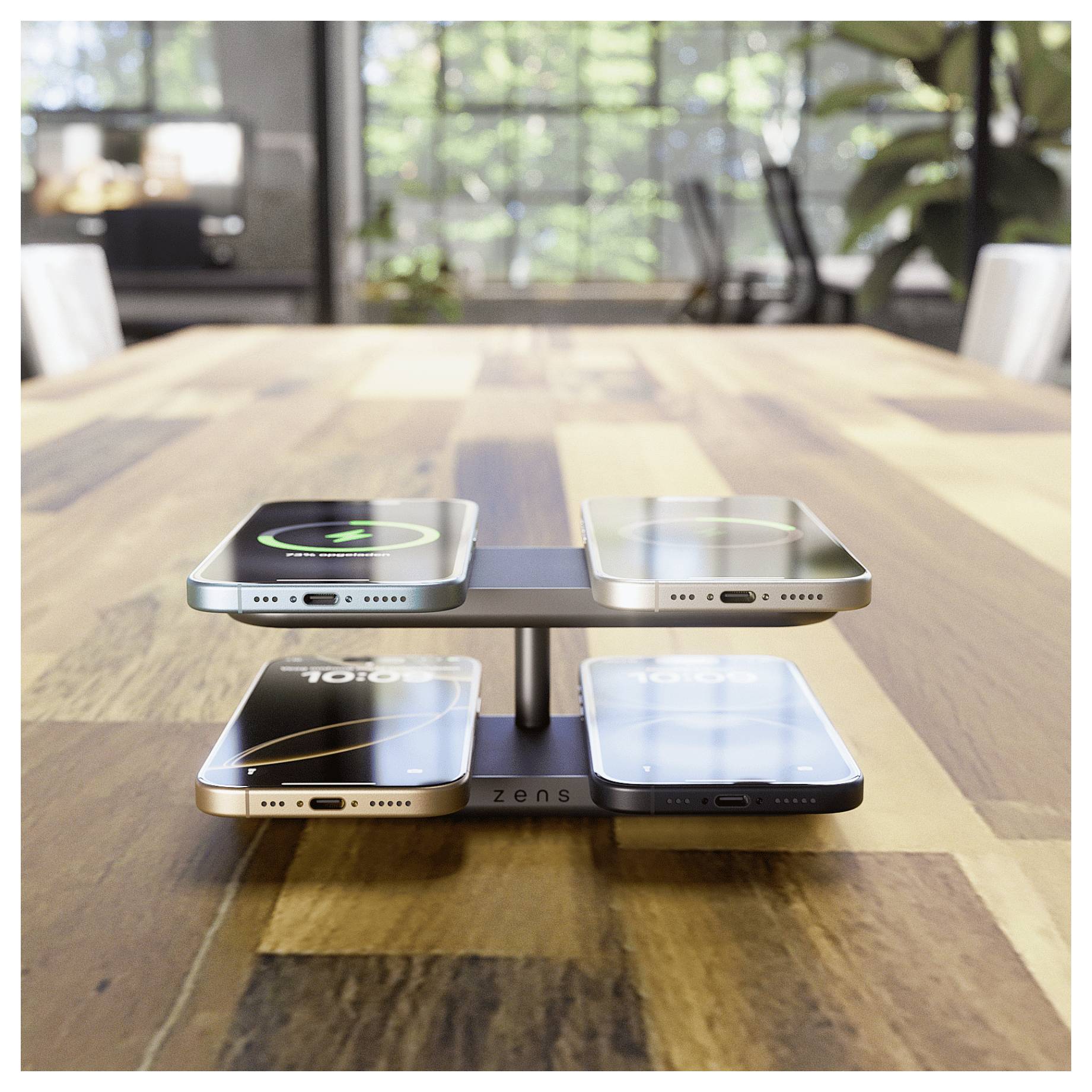 Bezprzewodowa stacja ładowania na drewnianym stole jednocześnie ładuje cztery smartfony, usytuowana w jasnym pomieszczeniu z dużymi oknami.