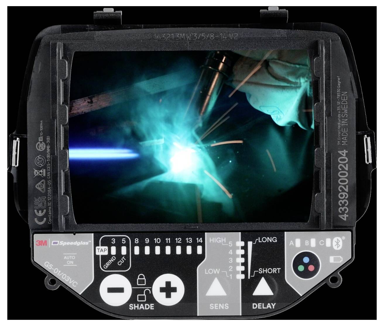 Spawacz pracuje z jasnym niebieskim światłem na metalu, widocznym przez interfejs obiektywu spawalniczego hełmu z widocznymi przyciskami sterowania.