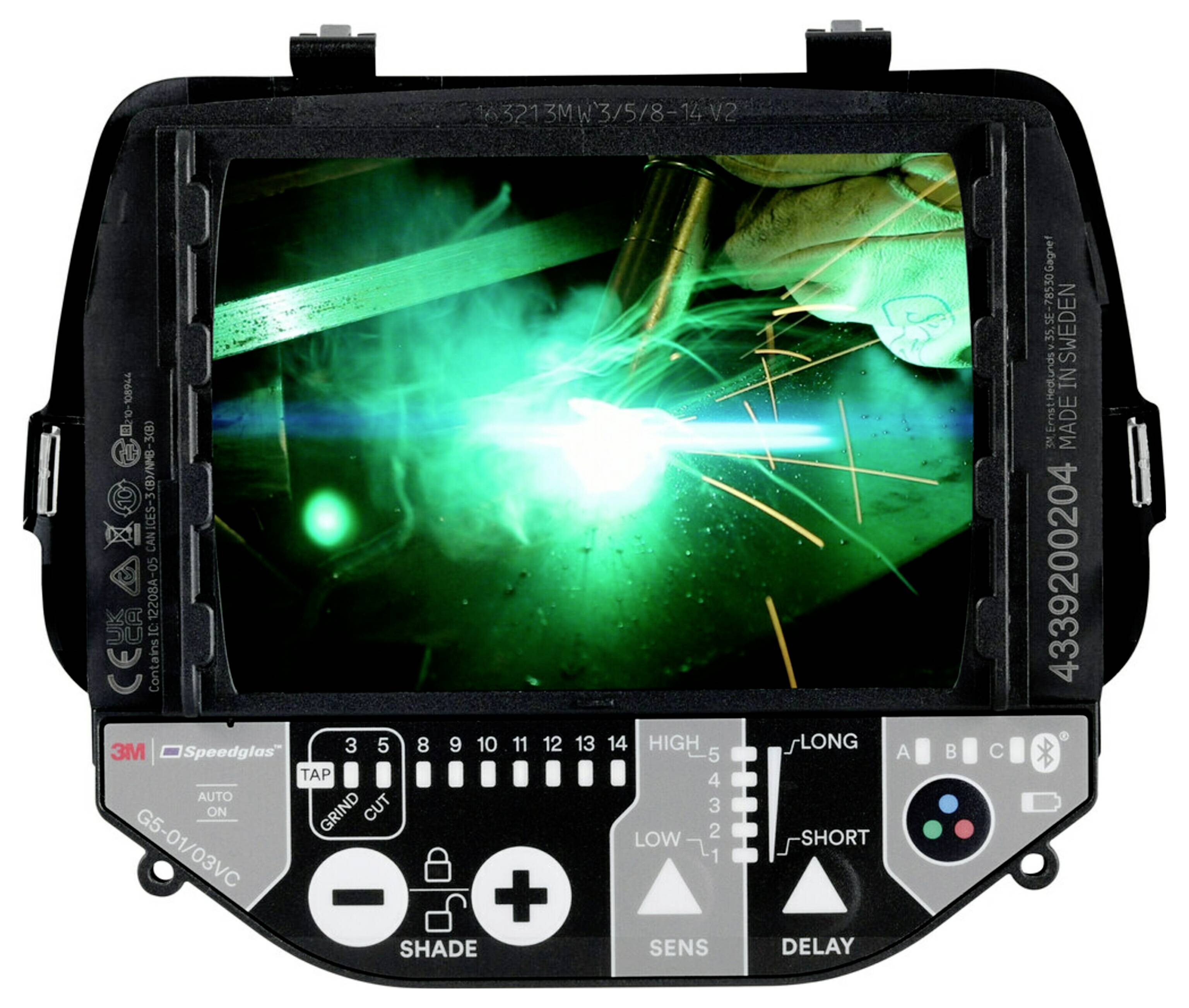 Spawacz pracuje, emitując jasne iskry i niebieskie światło. Widok jest przez ekran cyfrowego hełmu spawalniczego, z widocznymi przyciskami sterującymi poniżej.