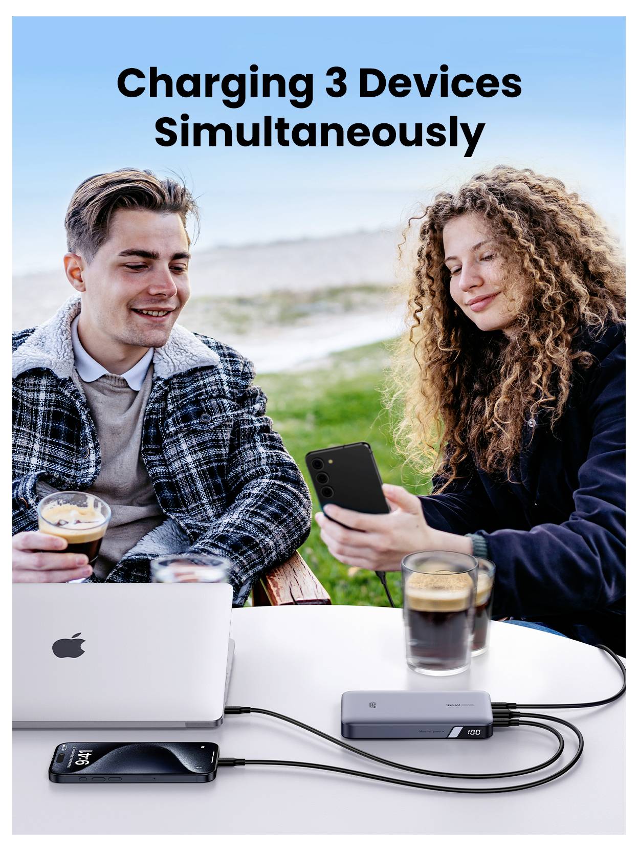 Dwóch ludzi siedzących na świeżym powietrzu, korzystających z laptopa i smartfonów. Centrum ładowania zasilające trzy urządzenia, ilustrujące jednoczesne ładowanie.