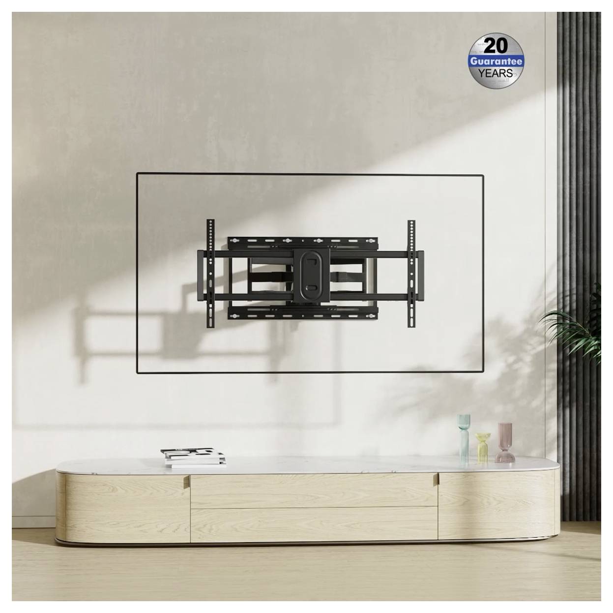 Uchwyt telewizyjny zamontowany na beżowej ścianie nad niską drewnianą szafką, z naklejką w prawym górnym rogu informującą o "20-letniej gwarancji".