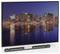 Na płaskim ekranie telewizora widać nocną panoramę miasta, z oświetlonymi budynkami i ich odbiciem w wodzie poniżej. Pod spodem zamontowany jest soundbar.