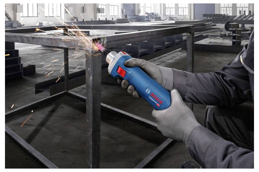 Osoba w rękawicach używa elektronarzędzia marki Bosch do szlifowania metalowej ramy, powodując przy tym iskrzenie, wewnątrz przemysłowego warsztatu.