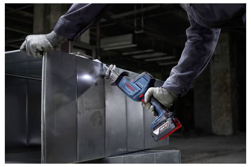 Osoba w rękawicach używa elektronarzędzia do cięcia arkuszy metalowych w środowisku przemysłowym, demonstrując wykorzystanie sprzętu.