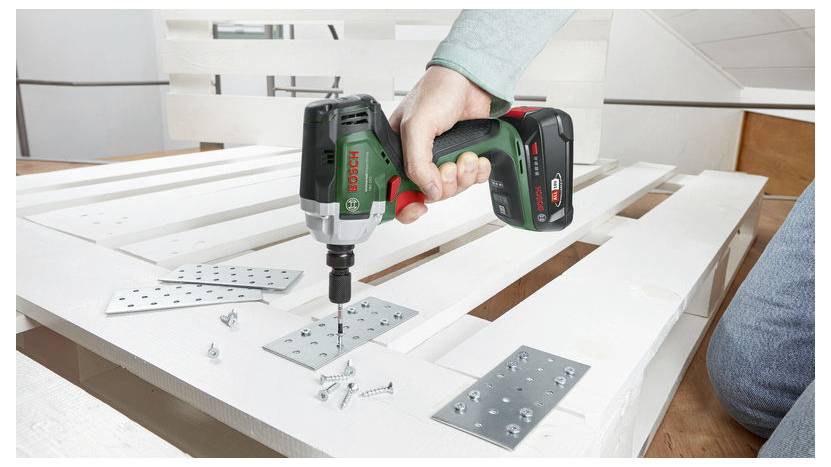 Osoba używająca wiertarki bezprzewodowej do przymocowania metalowych płyt do białych drewnianych listew za pomocą wkrętów. Projekt montażowy wydaje się być w toku.
