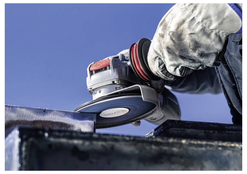 Osoba w rękawicach używa szlifierki kątowej na metalu, tworząc iskry na tle czystego, niebieskiego nieba.