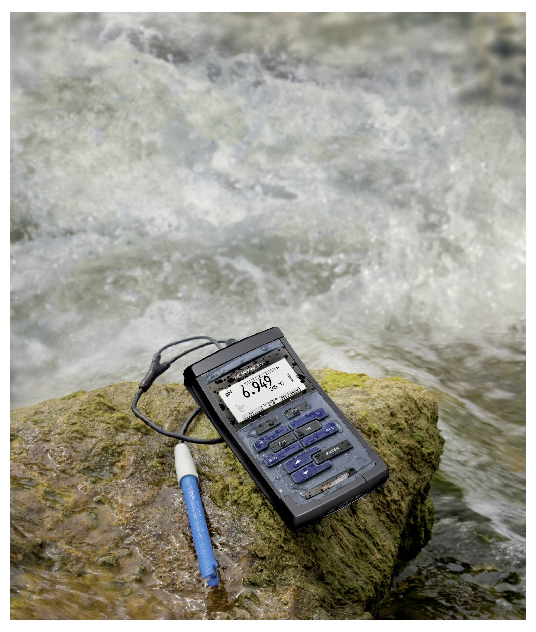 Miernik jakości wody i niebieski czujnik w kształcie pióra leżą na kamieniu obok płynącego strumienia, wyświetlając odczyt pH wynoszący 6,946.