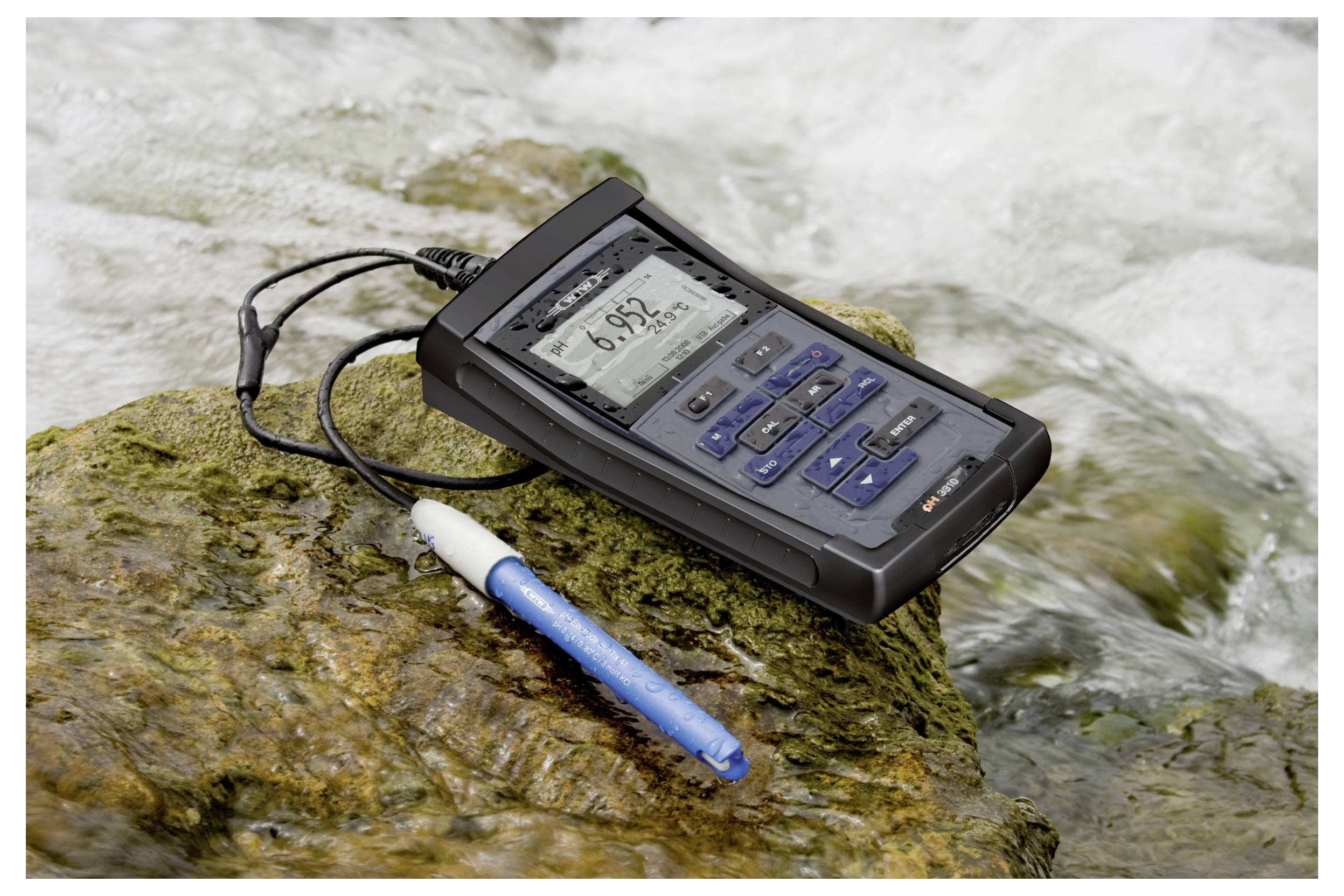 Przenośny cyfrowy miernik jakości wody wyświetla odczyt 6,92 na skalistej powierzchni przy płynącym strumieniu, obok niebieskiej sondy pomiarowej.