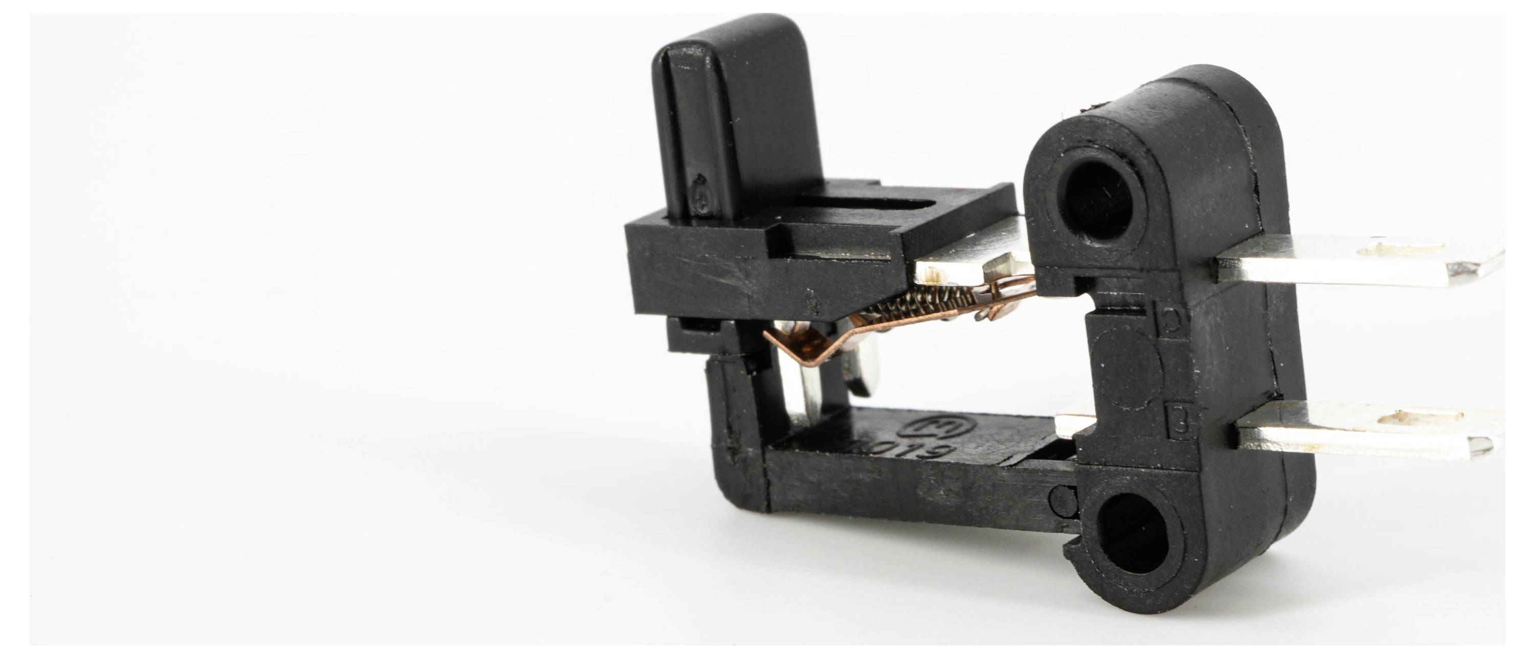 Czarny mikrowyłącznik na białym tle, z widocznymi miedzianymi elementami i metalowymi stykami.