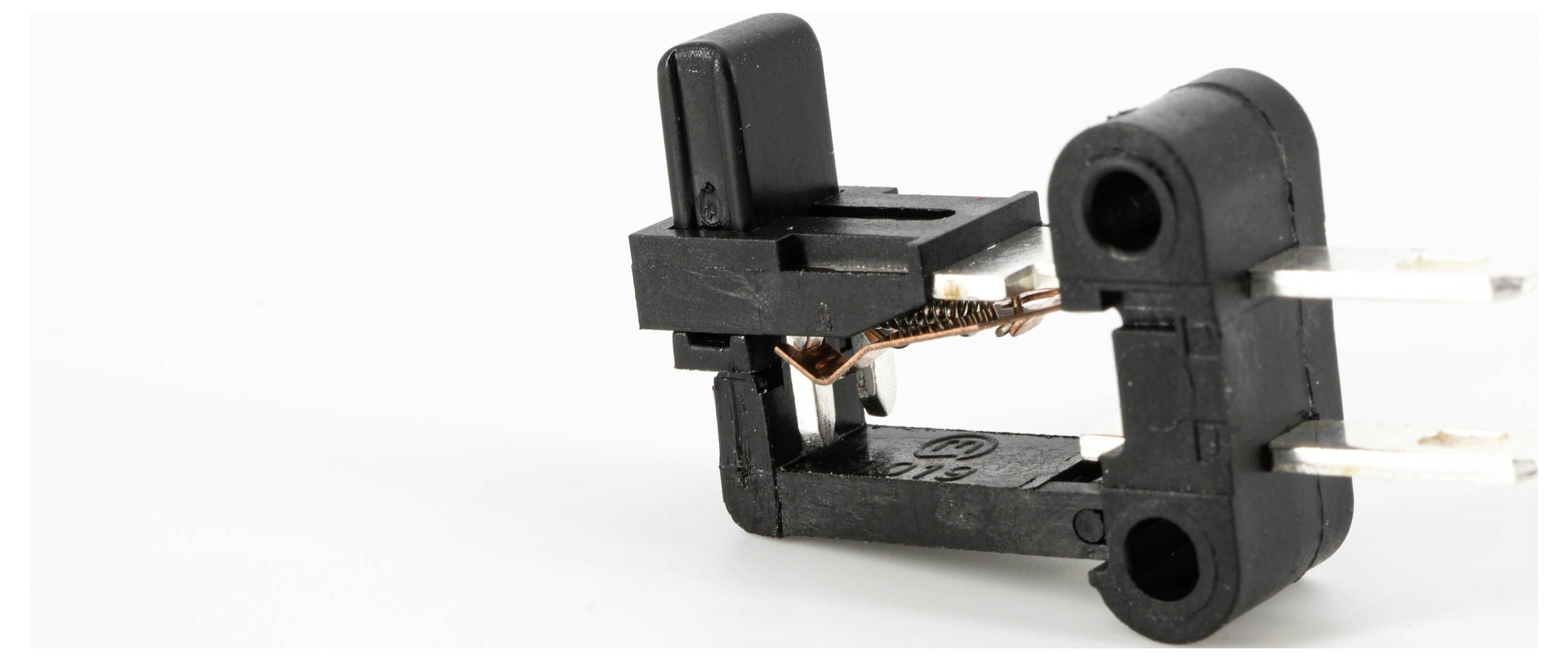 Czarny mikroswitch z widocznymi przewodami miedzianymi i metalowymi stykami, przeznaczony do połączeń elektrycznych.