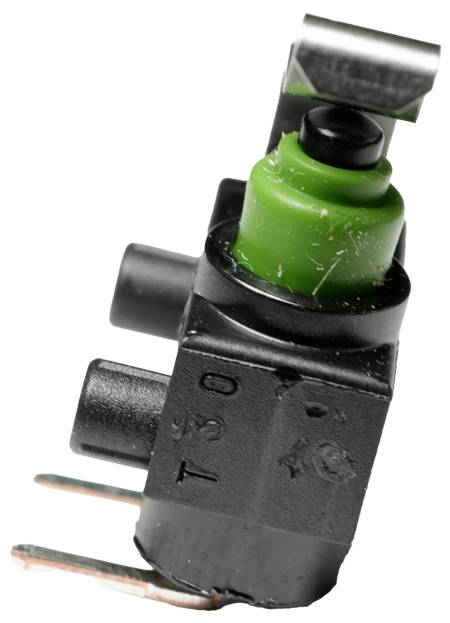 Zbliżenie małego, czarno-zielonego elementu elektrycznego z trzema stykami, powszechnie stosowanego w zastosowaniach motoryzacyjnych lub maszynowych.