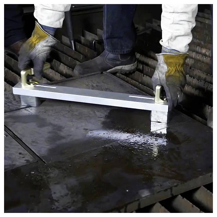 Osoba w rękawiczkach i odzieży ochronnej manipuluje metalowym elementem z hakami w środowisku przemysłowym.