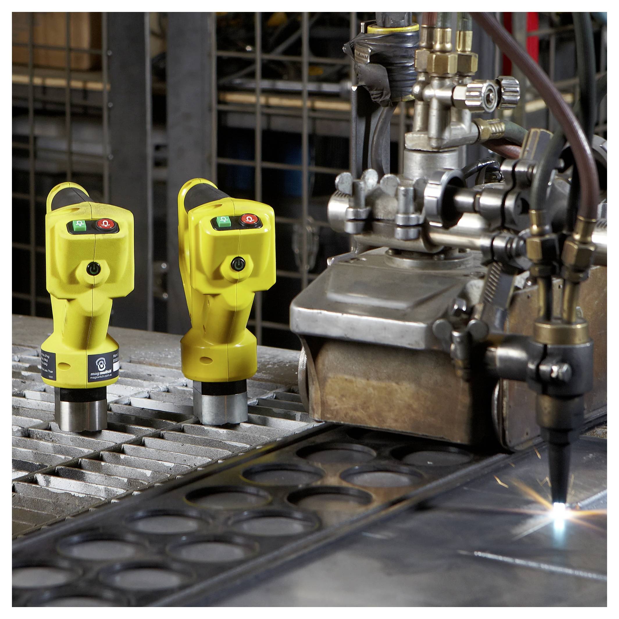 Przemysłowa maszyna tnąca aktywnie pracująca na arkuszach metalu, z dwoma żółtymi czujnikami bezpieczeństwa w pobliżu do monitorowania operacji.