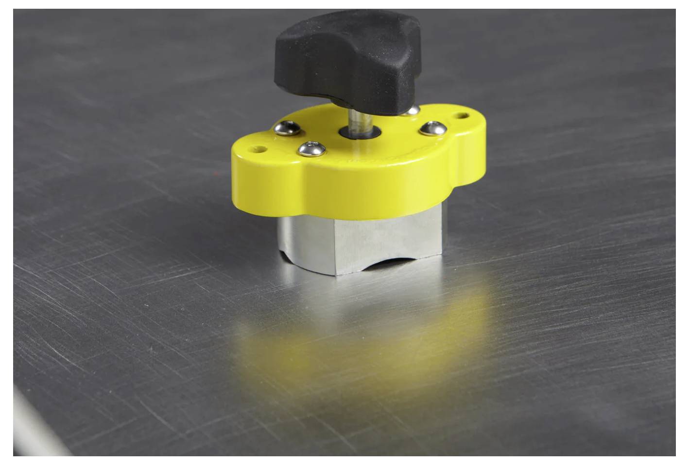 Żółta metalowa zatrzaśka z czarną rączką zabezpiecza powierzchnię metalowej blachy.