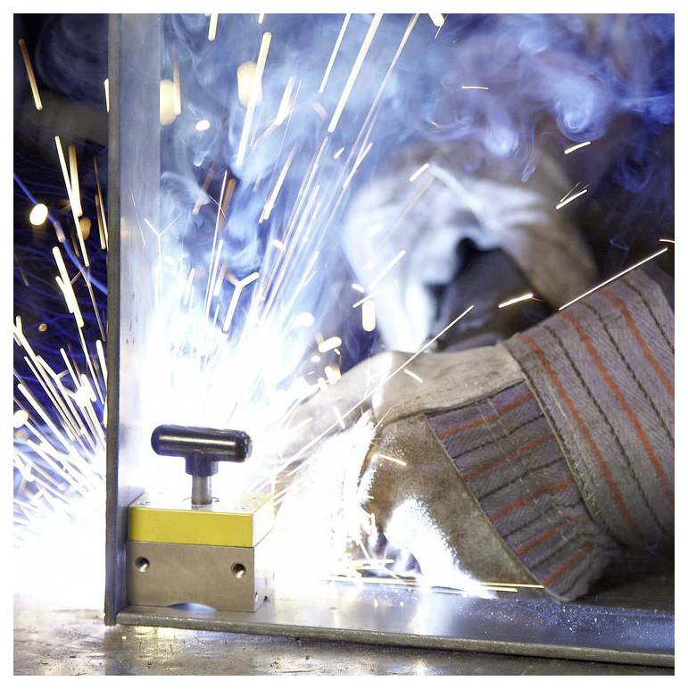 Osoba spawająca metal z intensywnymi iskrami i mocnym światłem, ubrana w ochronne rękawice. Scena podkreśla pracę przemysłową i bezpieczeństwo.