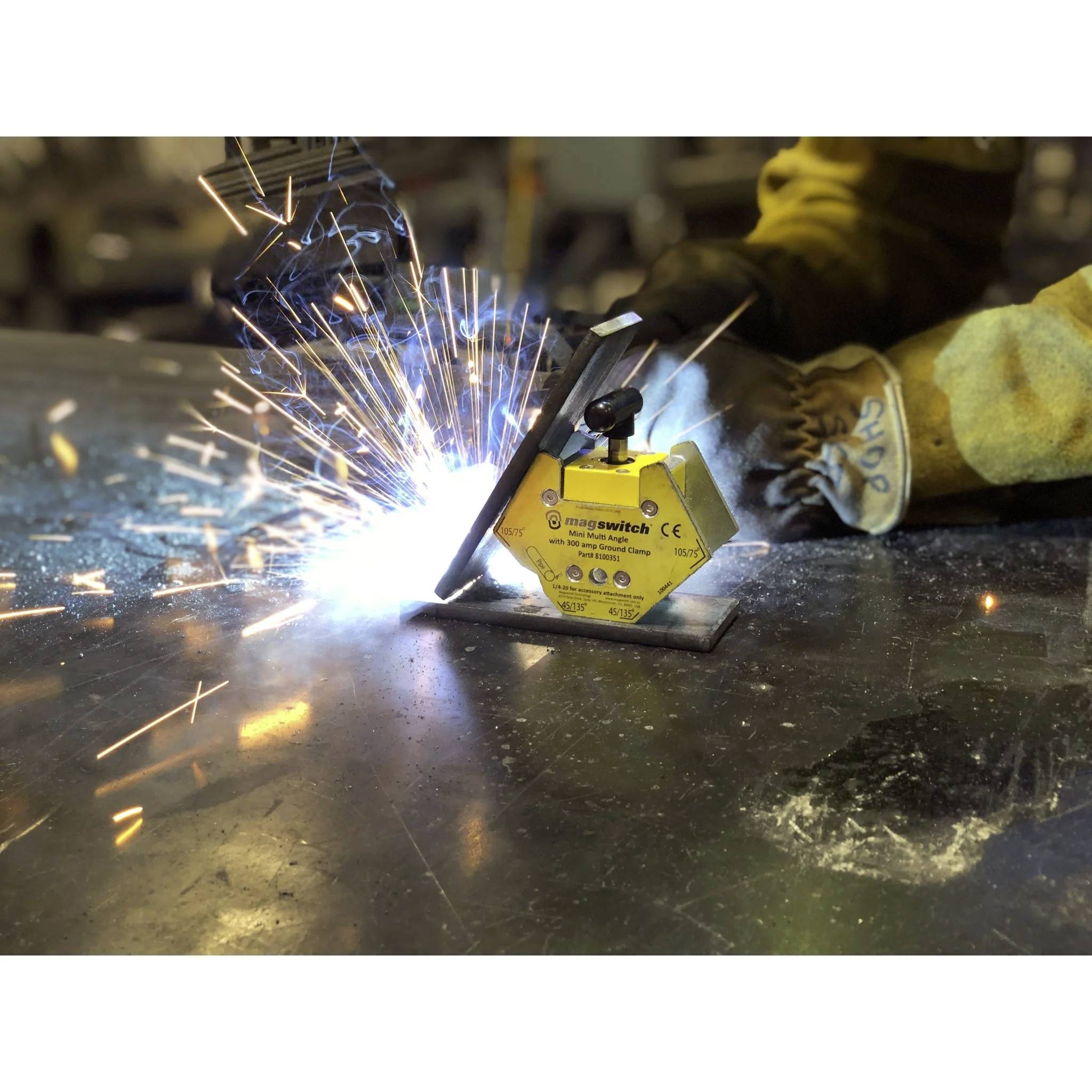 Osoba w ochronnych rękawicach prowadzi narzędzie spawalnicze, tworząc jasne iskry na metalowej powierzchni w przemysłowym otoczeniu.