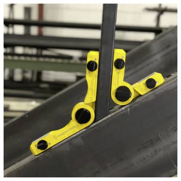 Żółty magnetyczny kątomierz przylega do dwóch przecinających się metalowych belek, wyświetlając kąt złączenia dla wyrównania w budownictwie.