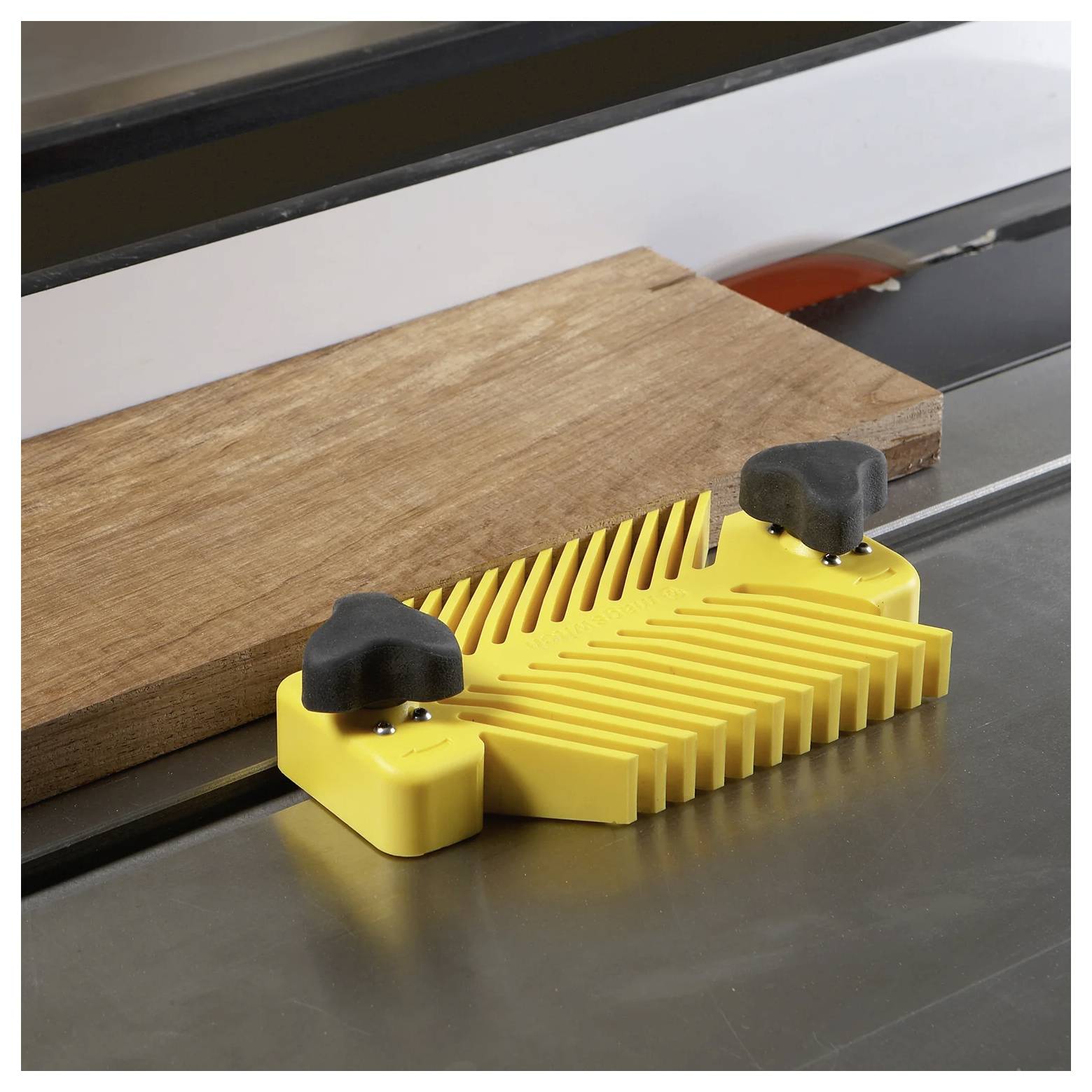 Piła stołowa prowadzi kawałek drewna za pomocą żółtego prowadnika, zapewniając proste, kontrolowane cięcia. Domyślne jest użycie sprzętu ochronnego.