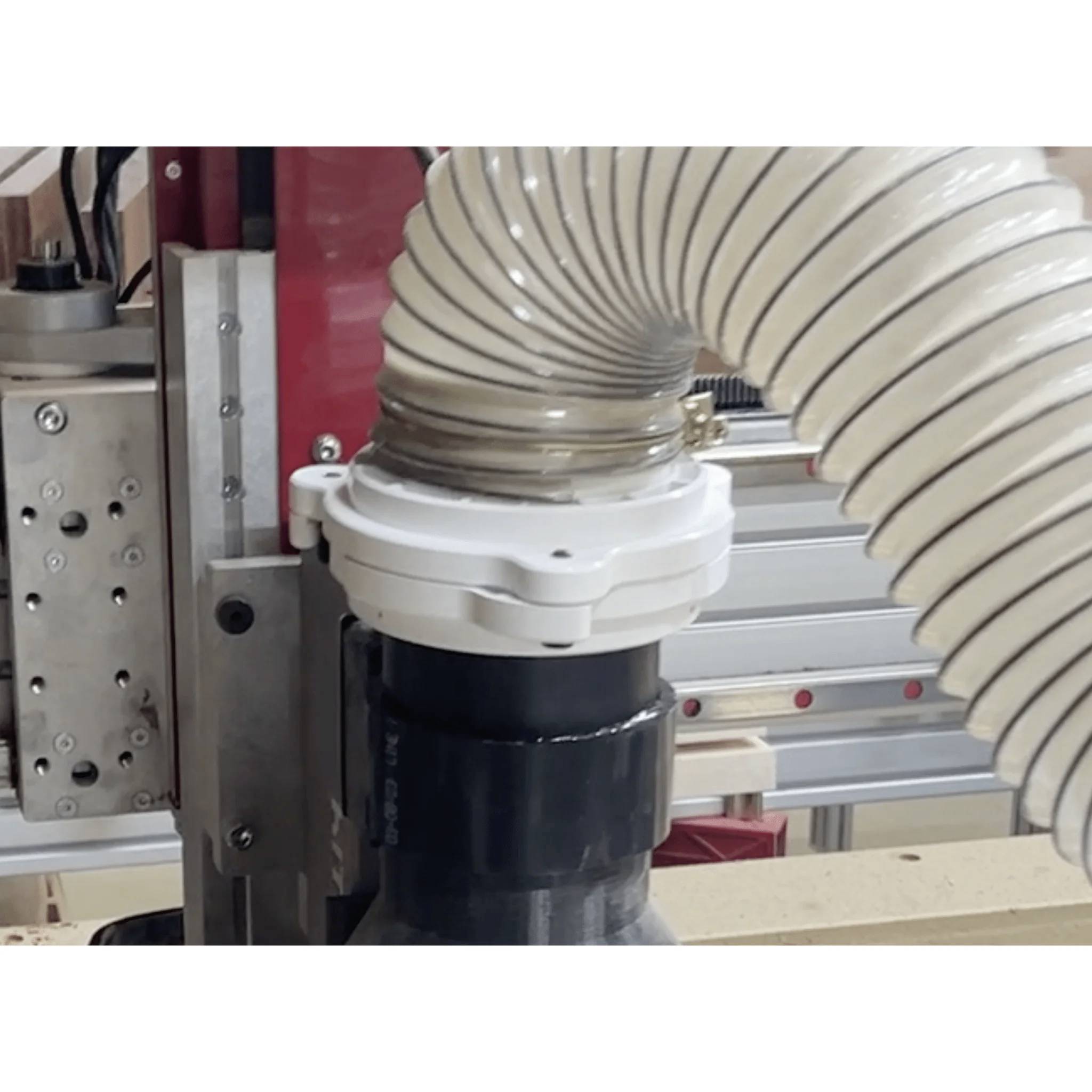 System odpylania obrabiarki CNC podczas pracy, z elastycznym wężem podłączonym do wrzeciona, zapobiegający gromadzeniu się pyłu.