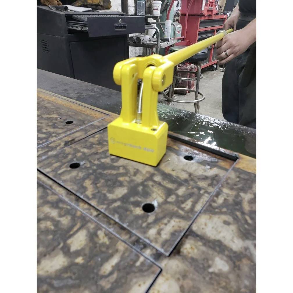Osoba obsługuje żółty podnośnik magnetyczny Magnetic 400 do przenoszenia arkusza metalu w warunkach warsztatowych.