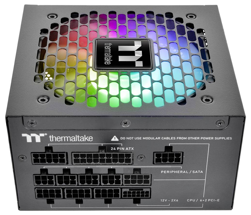 Jednostka zasilająca komputera z kolorowym wentylatorem LED na wierzchu, wyposażona w liczne porty do podłączania kabli, oznaczona napisem 'Thermaltake'.