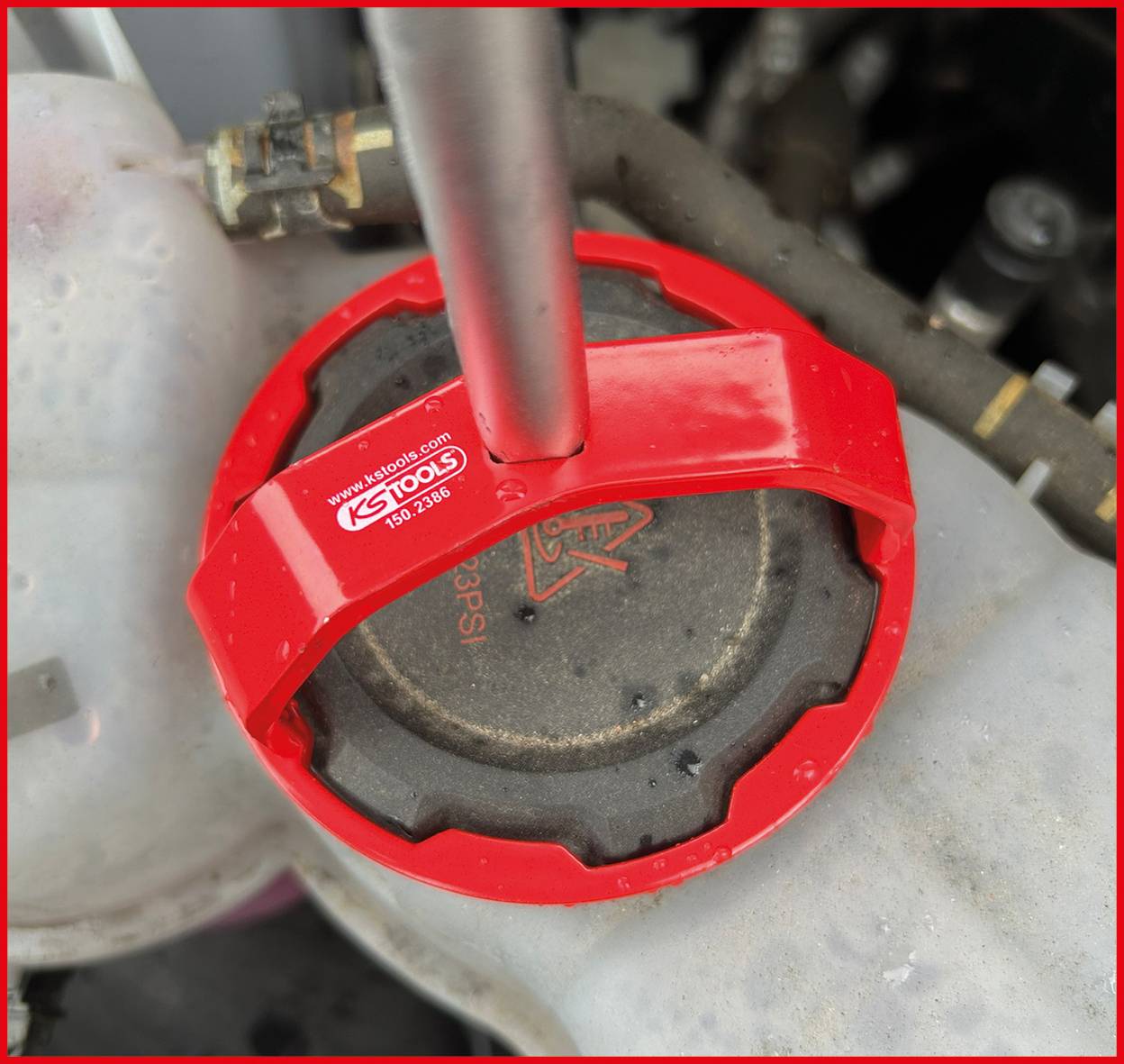 Czerwony klucz nastawny KS Tools mocno trzyma szary korek wlewu oleju silnikowego, przygotowany do poluzowania lub dokręcenia, prezentując czynność konserwacji silnika.