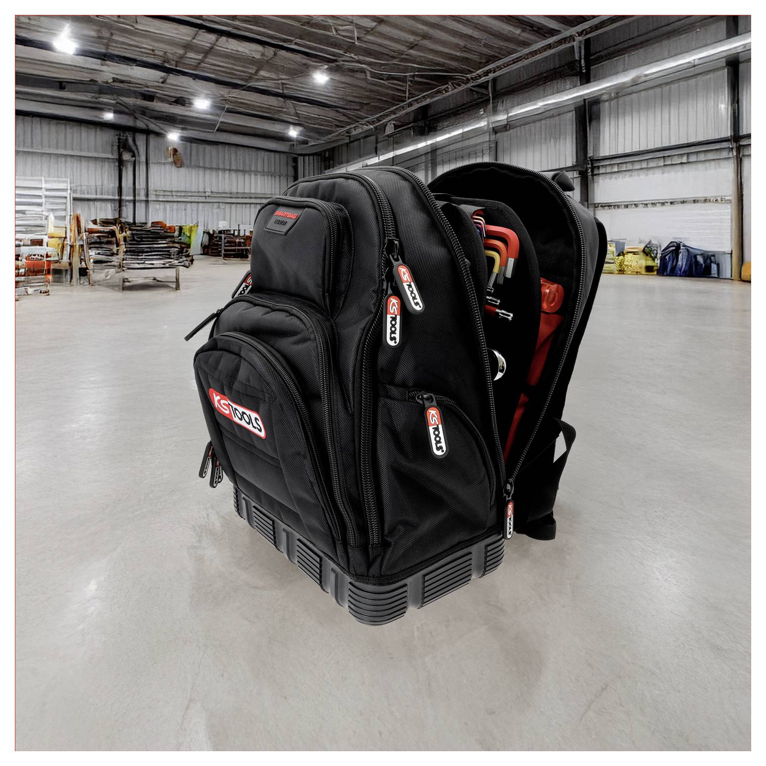 Czarny plecak z wieloma kieszeniam, lekko otwarty, ukazujący narzędzia w środku. Stoi na czystej podłodze magazynu.