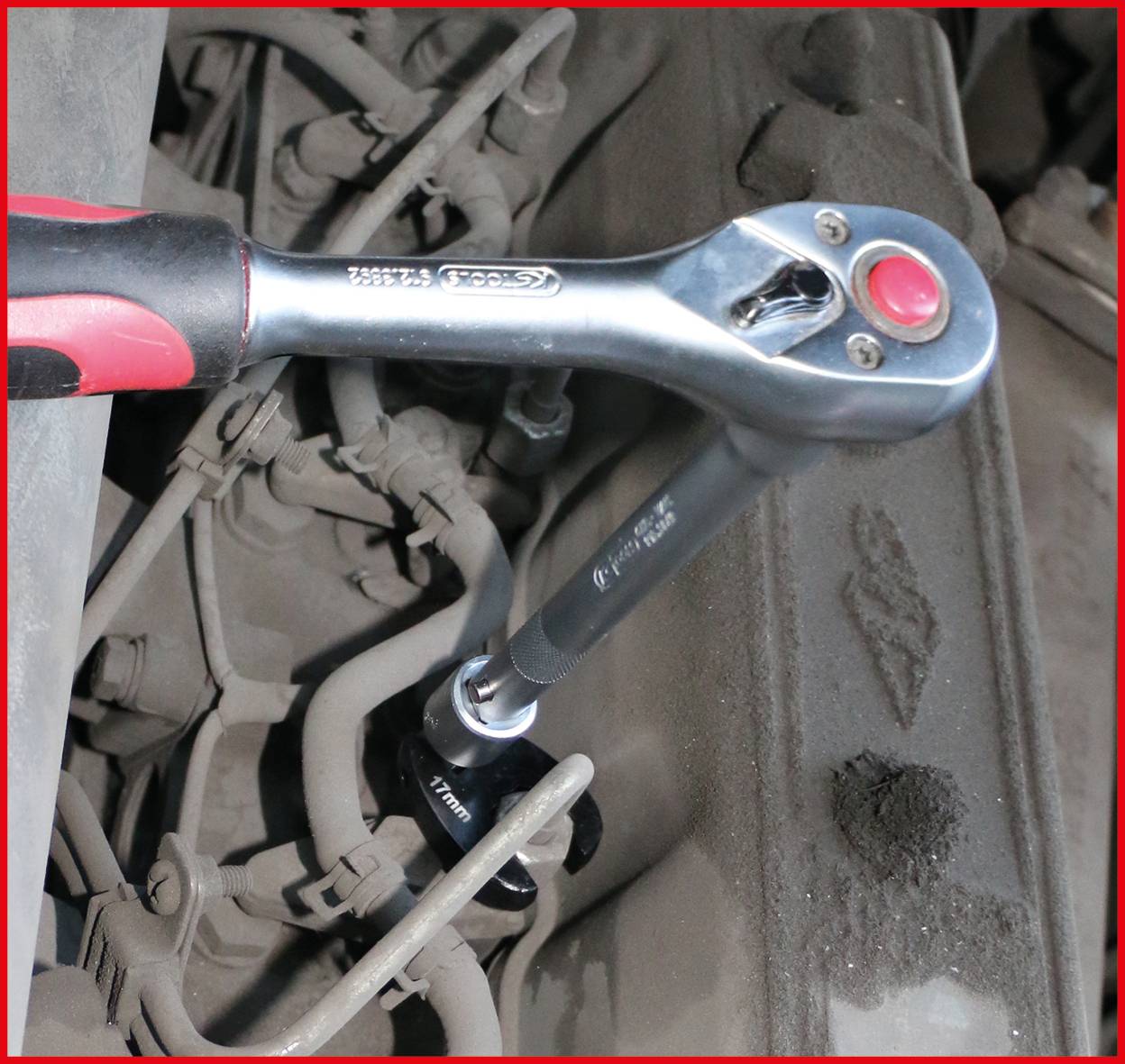 Klucz z mechanizmem zapadkowym dokręcający śrubę w silniku samochodu, ilustrujący czynności serwisowe.