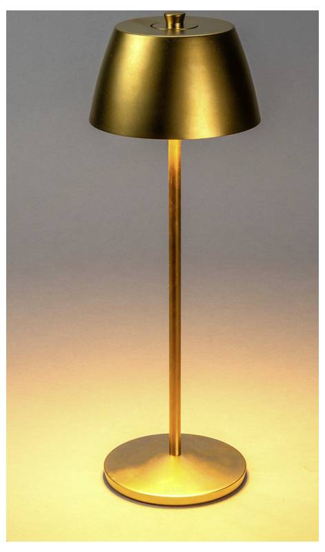 Złota metaliczna lampa stołowa o prostym designie rzuca ciepłe, miękkie światło na powierzchnię poniżej, tworząc przytulną atmosferę.