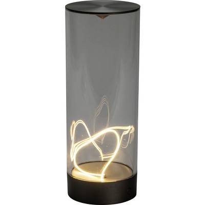 Cylindryczna szklana lampa z żarzącą się włókną wewnątrz, kształtem przypominająca abstrakcyjne linie, osadzona na gładkiej metalowej podstawie, na tle prostej, jednolitej przestrzeni.