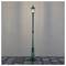 Pojedyncza stylowa lampa uliczna w stylu vintage z jasno świecącym światłem, stojąca na brukowanej ścieżce na tle prostego, jednobarwnego tła.