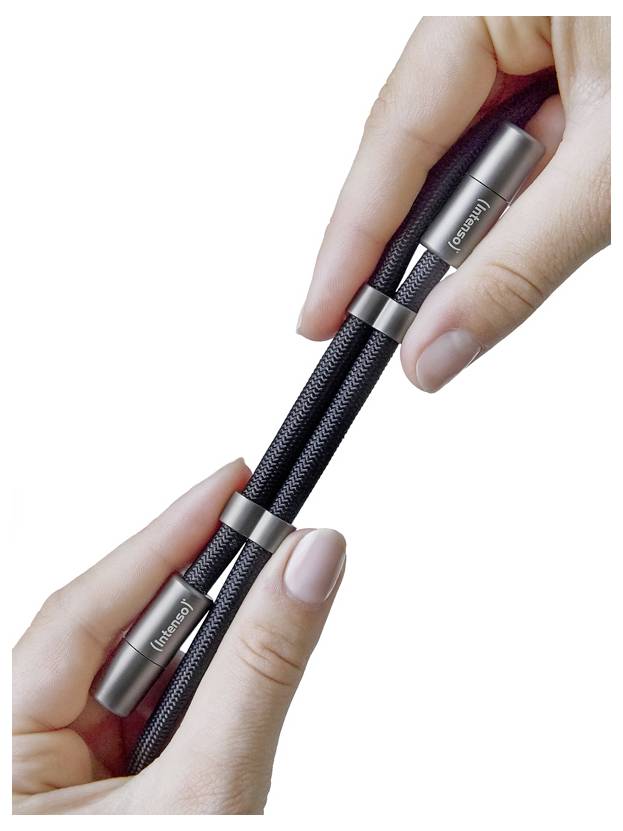 Dłonie trzymające czarną siatkową zabawkę antystresową z metalowymi końcówkami, oznaczoną napisem 'inhand'.