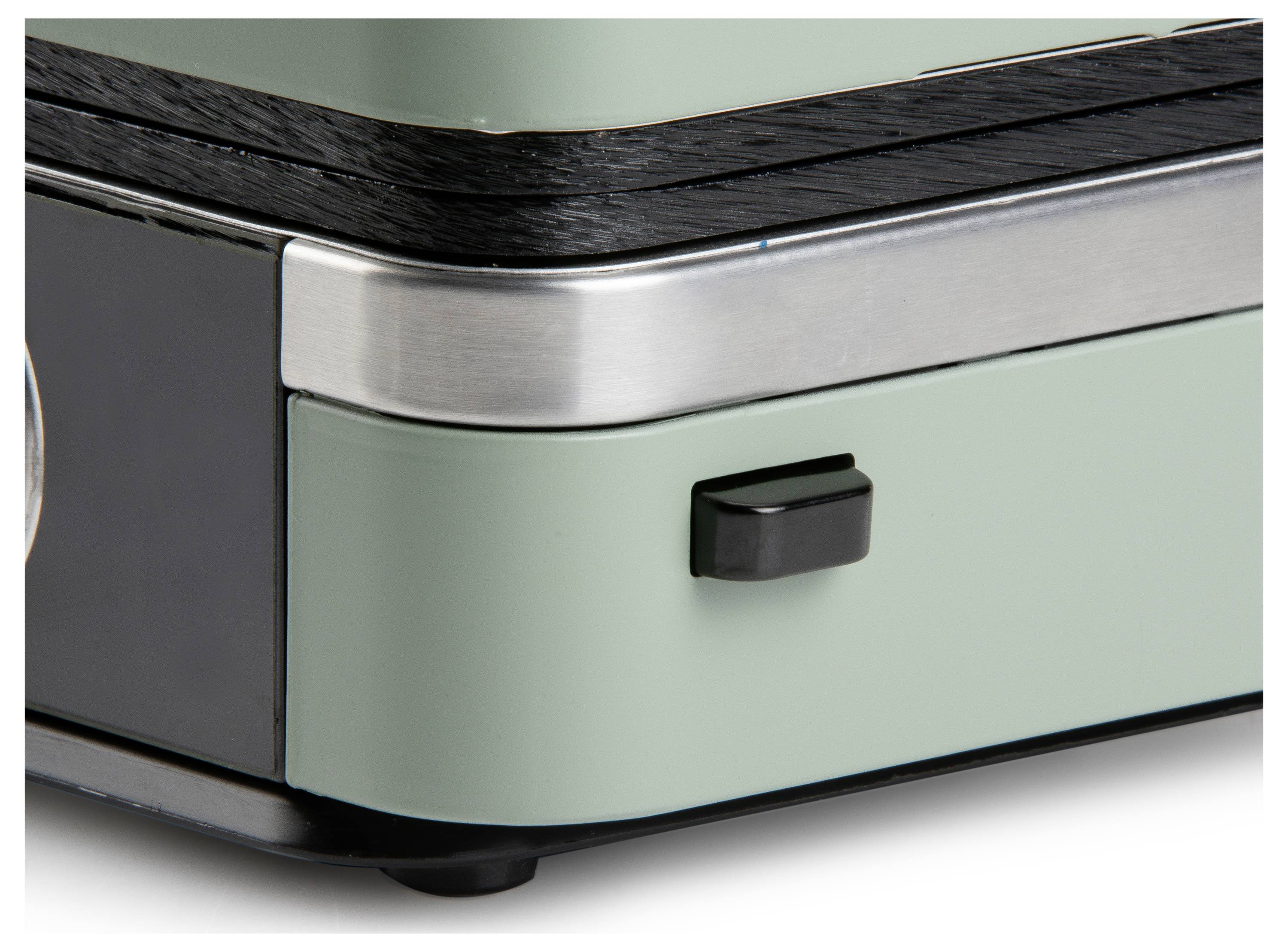 Zbliżenie zielonego i czarnego narożnika urządzenia elektronicznego w stylu retro z małym czarnym przełącznikiem i metalową obramówką.