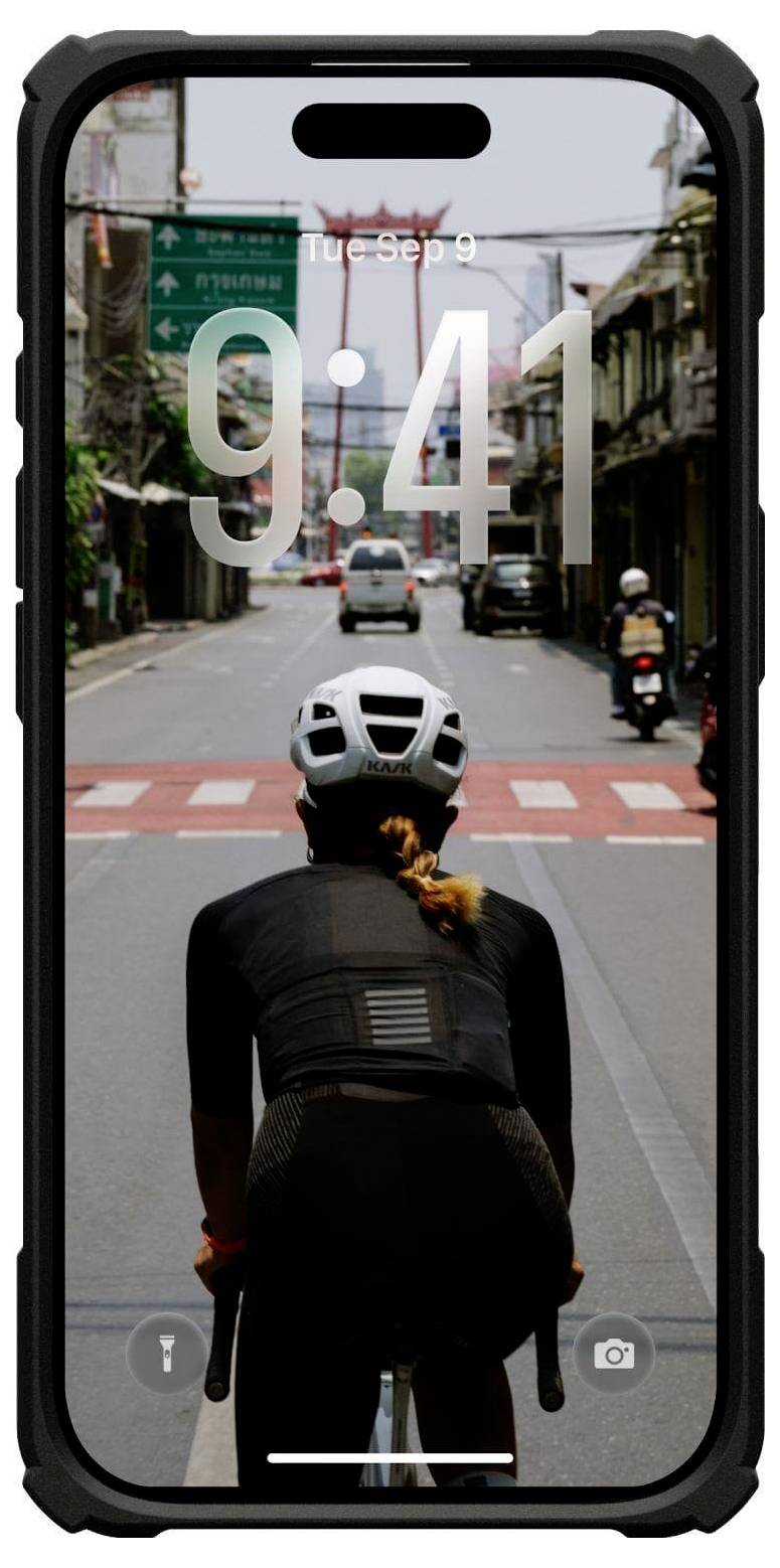 Rowerzysta w czarnym stroju jedzie ulicą miasta w kierunku przejścia dla pieszych, widoczny przez ekran smartfona wyświetlający godzinę 9:41 i datę "Wt, Wrz 9".