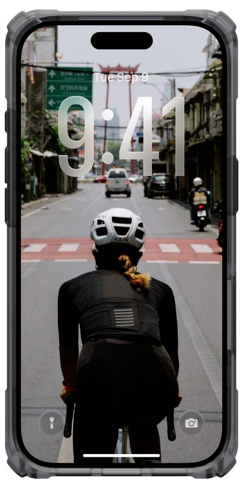 Osoba jadąca na rowerze ulicą, widziana od tyłu, wyświetlana na ekranie smartfona, na którym widnieje godzina '9:41' oraz data 'Wt, Wrz 9'.