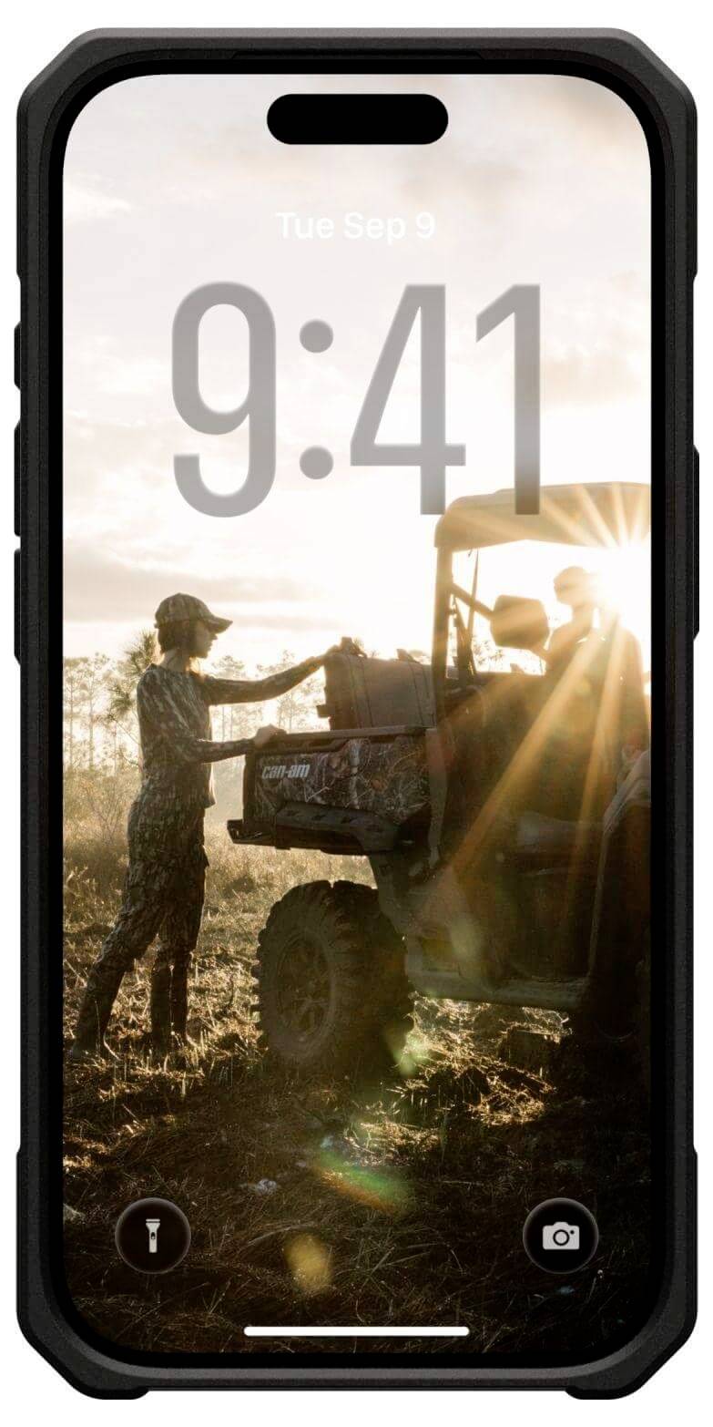 Osoba stoi w pobliżu samochodu terenowego na polu o wschodzie słońca, z wyposażeniem w bagażniku i promieniami słońca przechodzącymi przez krajobraz.