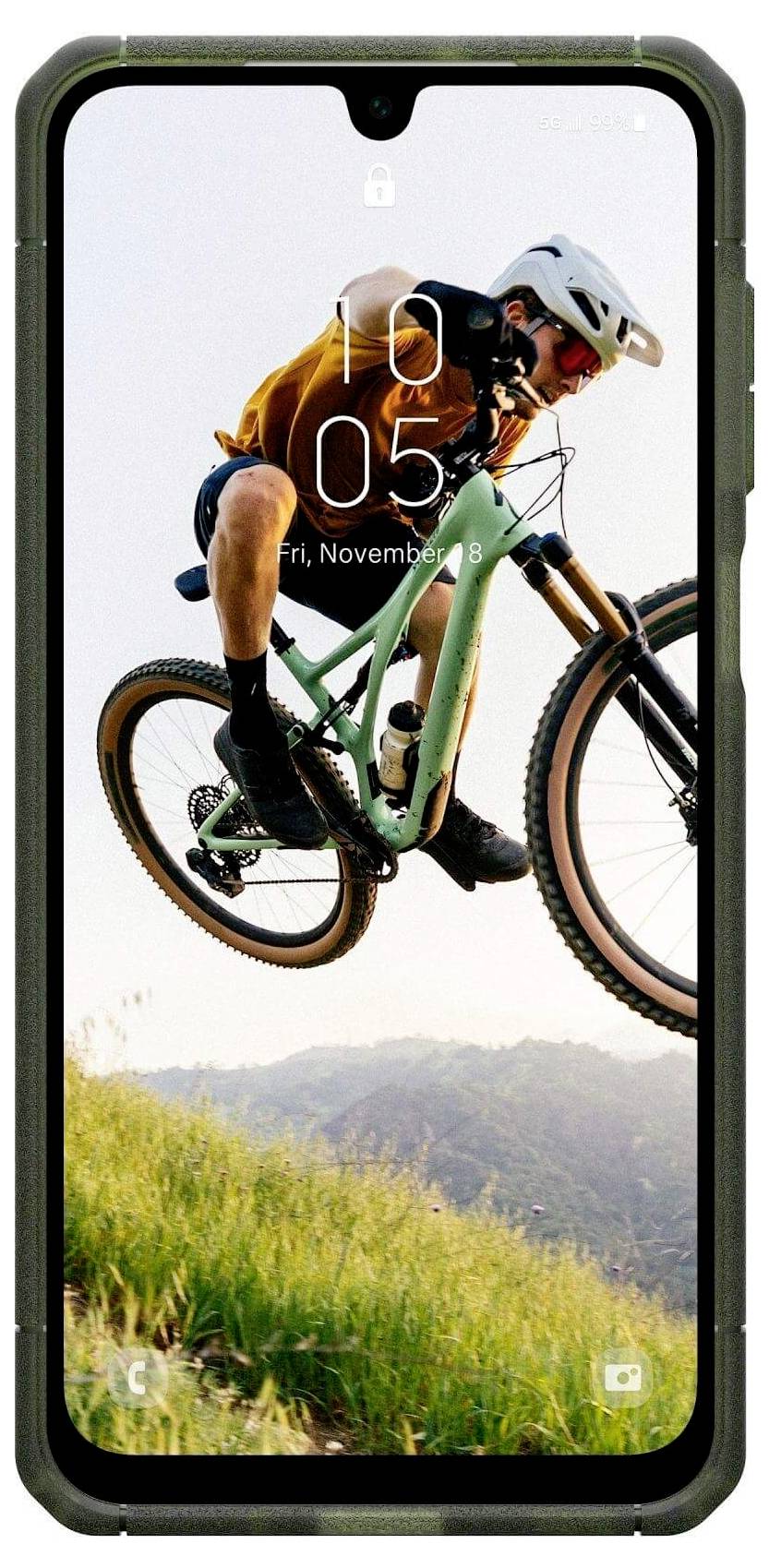 Rowerzysta górski w locie nad trawiastym wzgórzem, ubrany w kask i ochraniacze, z nakładką interfejsu smartfona wyświetlającą godzinę i datę.