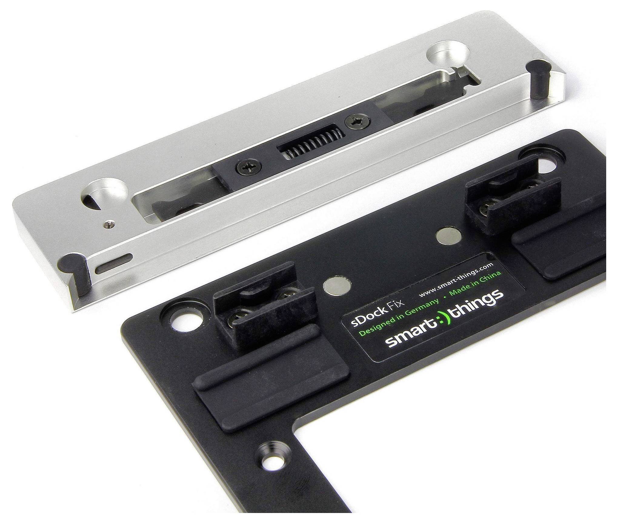 Mocowania dla 'sDock Fix' firmy smart things, prezentujące metalowy wspornik i czarny komponent z oznakowaniem i funkcjami regulacji.