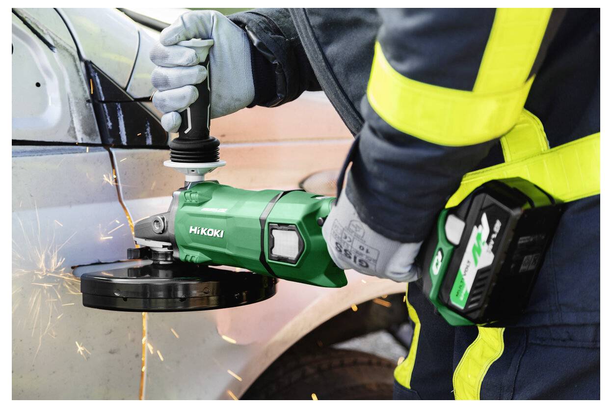 Osoba w odzieży ochronnej używa zielonej szlifierki kątowej HiKOKI do cięcia metalu, wytwarzając przy tym snop iskier. Nacisk położony jest na narzędzie i wykonywaną czynność.
