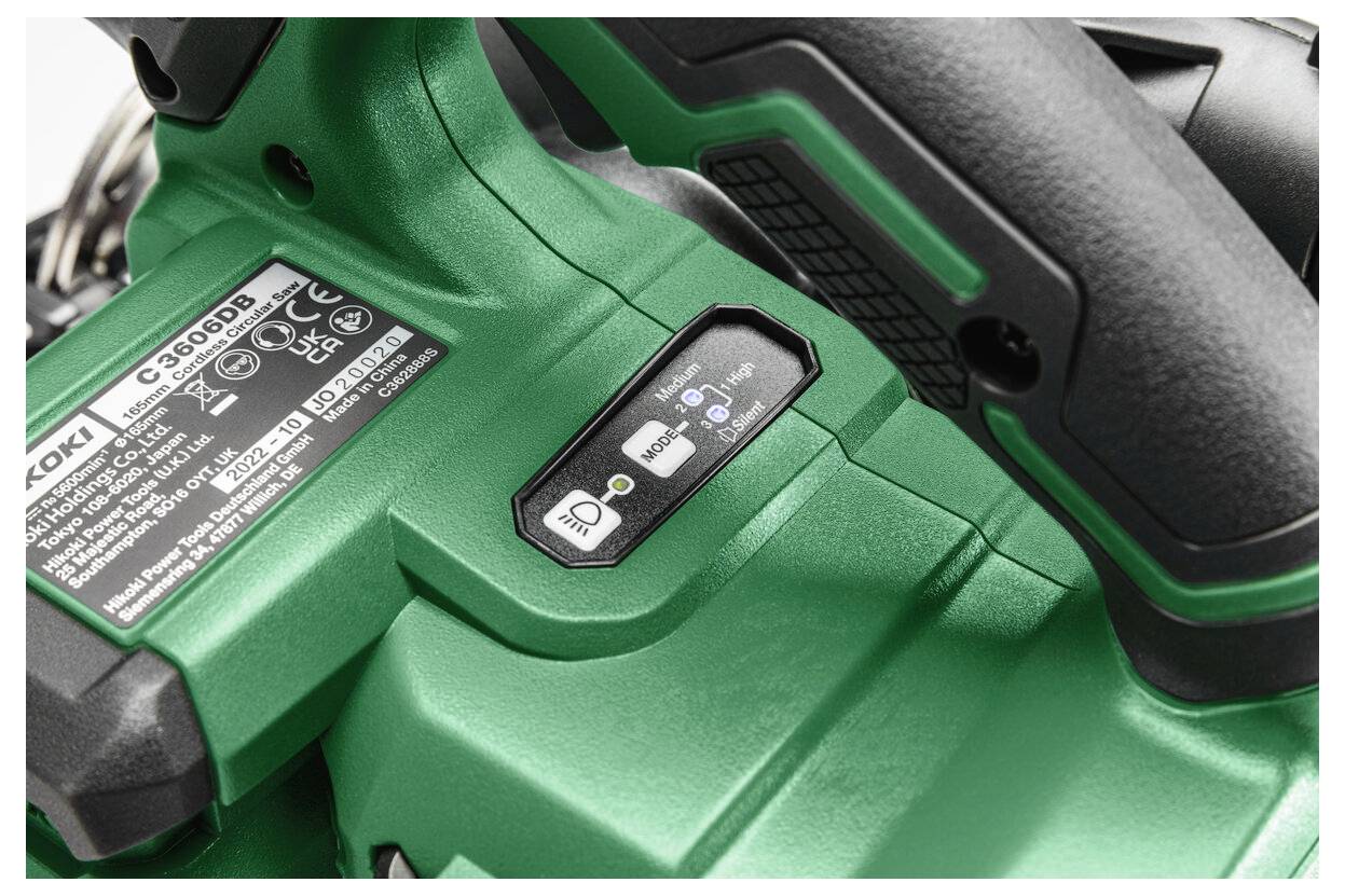 Zbliżenie zielonego narzędzia elektrycznego z przełącznikiem sterującym, etykietą produktu oraz tekstem wskazującym instrukcje dotyczące akumulatora i bezpieczeństwa.