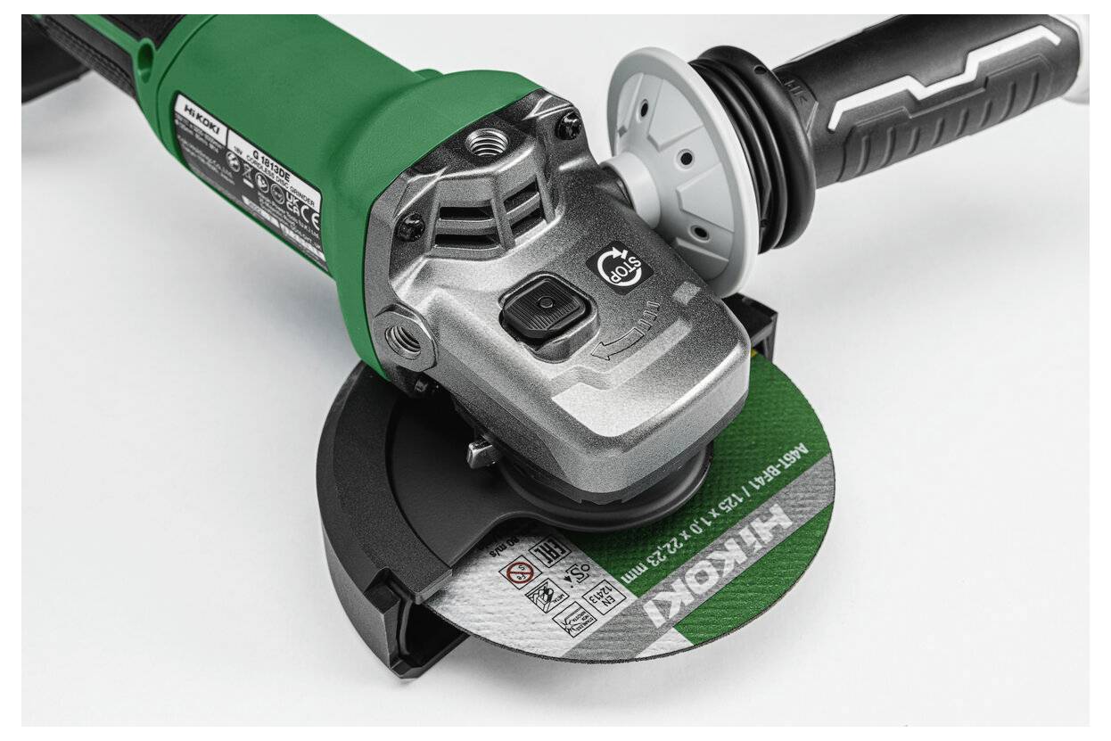 Zbliżenie kątnicy z zieloną tarczą, przedstawiające narzędzie do cięcia metalu. Widoczne są szczegóły uchwytu i obudowy silnika.